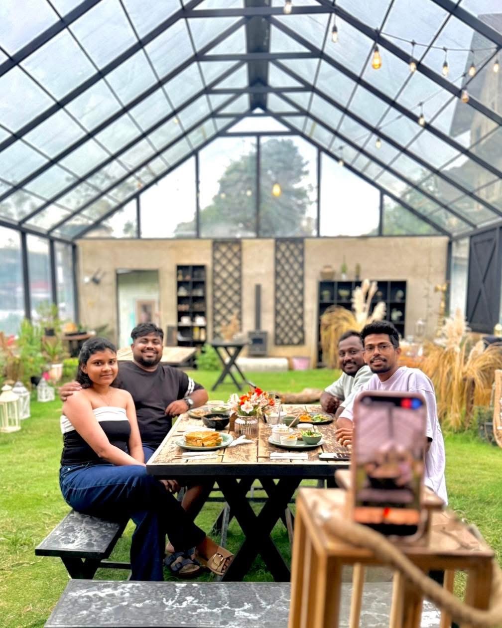 Guests sharing a meal at a long table inside the greenhouse